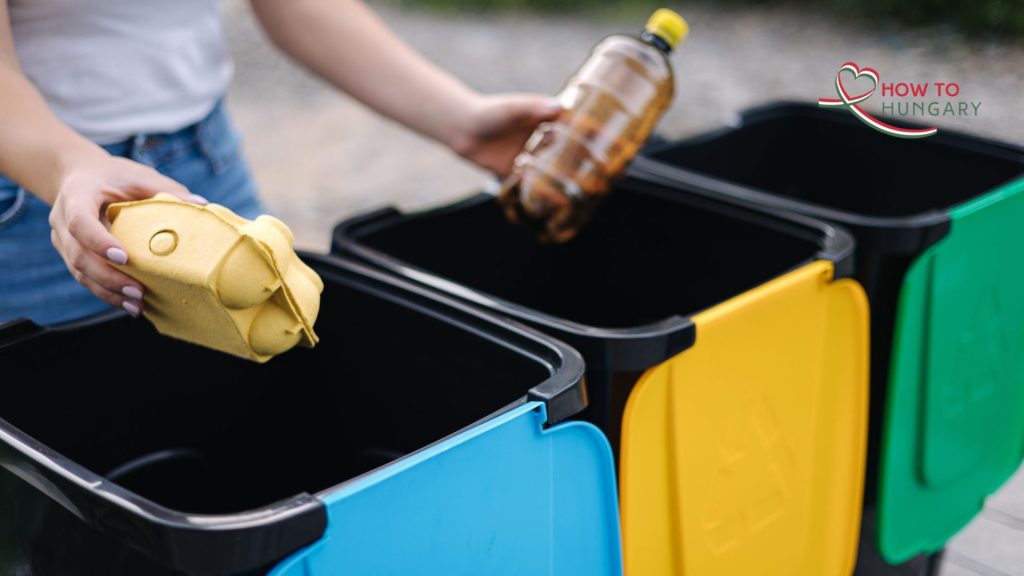 Resident sorting paper, plastic and metal into labelled recycling bins in Budapest.