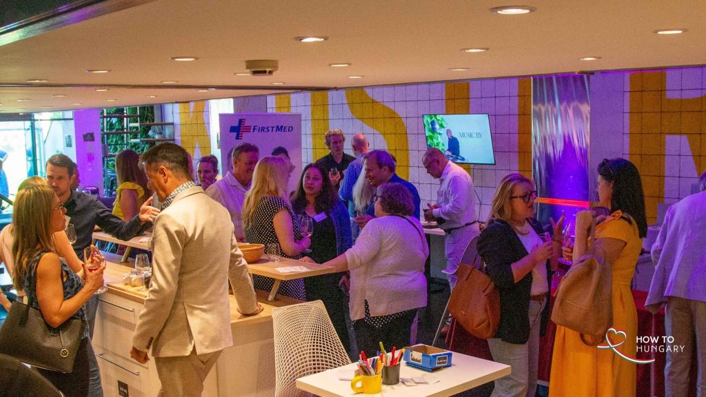 A packed room of guests mingling at the HOW TO HUNGARY Spring Social, KLUSTER Budapest, supported by FirstMed.