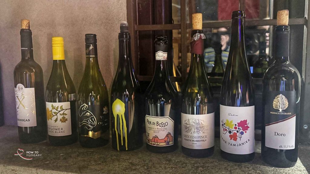 Eight tasting wines lined up on a windowsill at the Memento Park wine tasting in Budapest, four Hungarian and four international.