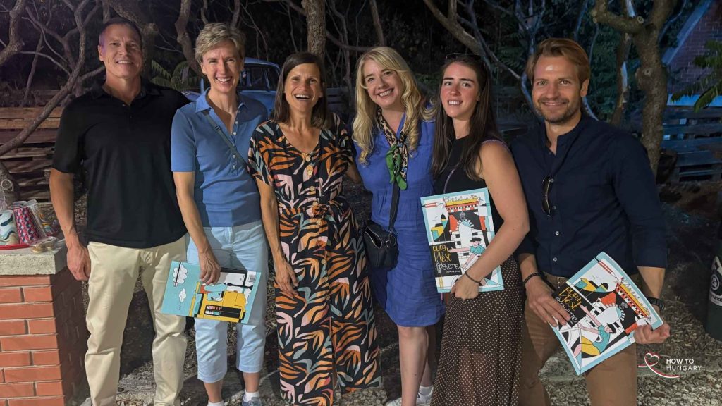 Guests at the Memento Park wine tasting in Budapest holding Buda Pest colouring books after dark.