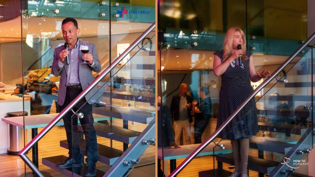 FirstMed CEO Dennis Diokno and host Anikó Woods giving a toast on the staircase at the HOW TO HUNGARY September Social, KLUSTER Budapest.